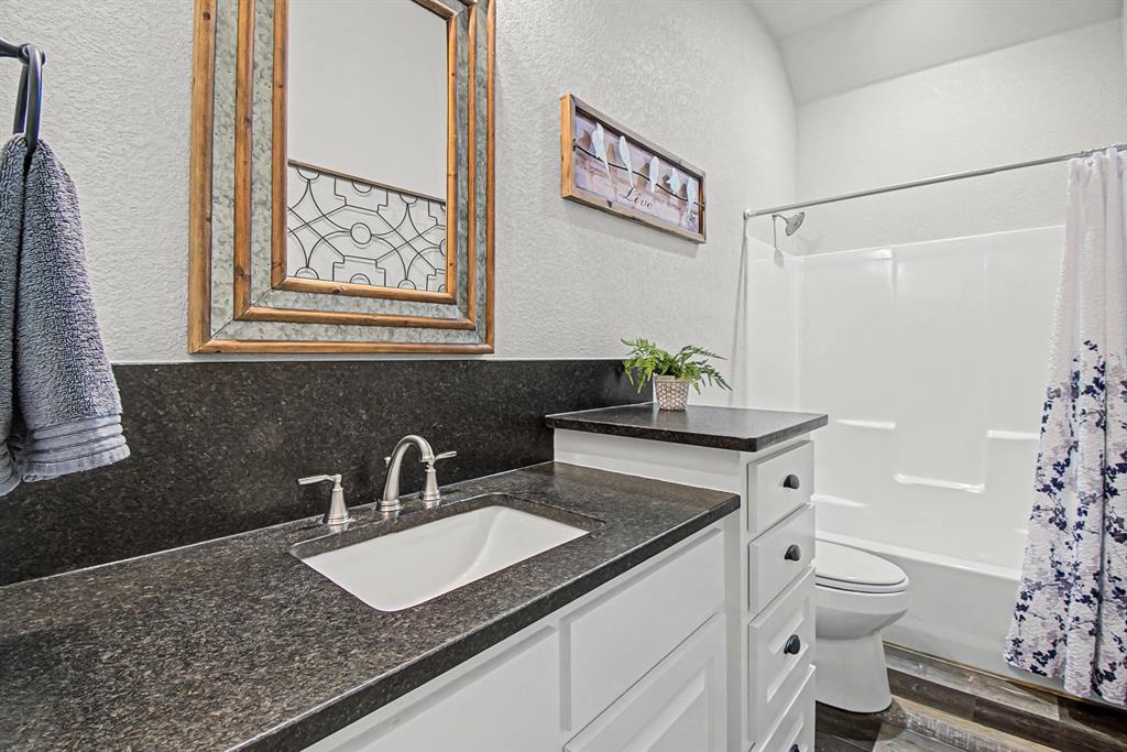 793 County Road 2535 Decatur, TX 76234 - Photo 26 of 39 a bathroom with a granite countertop sink a toilet and a mirror