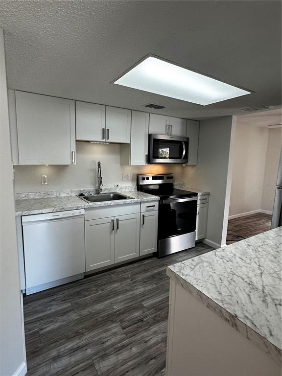 124 Loblolly Court, Unit F Oldsmar, FL 34677 - Photo 15 of 33 a kitchen with granite countertop a stove top oven a sink dishwasher and a refrigerator with wooden floor
