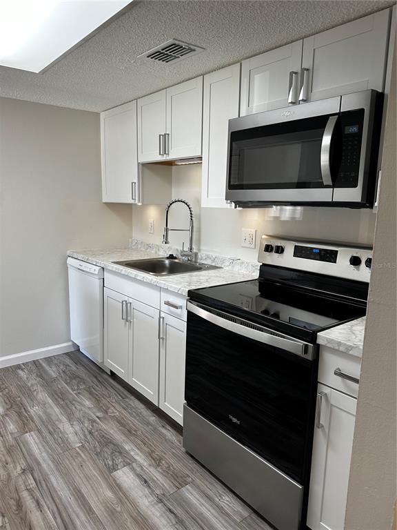 124 Loblolly Court, Unit F Oldsmar, FL 34677 - Photo 23 of 33 a kitchen with stainless steel appliances a stove a microwave a sink and cabinets