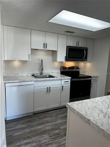 a kitchen with a refrigerator a sink and dishwasher with wooden floor