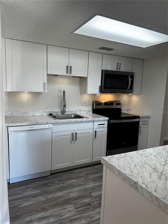 124 Loblolly Court, Unit F Oldsmar, FL 34677 - Photo 30 of 33 a kitchen with kitchen island granite countertop a sink a stove a microwave and wooden cabinets