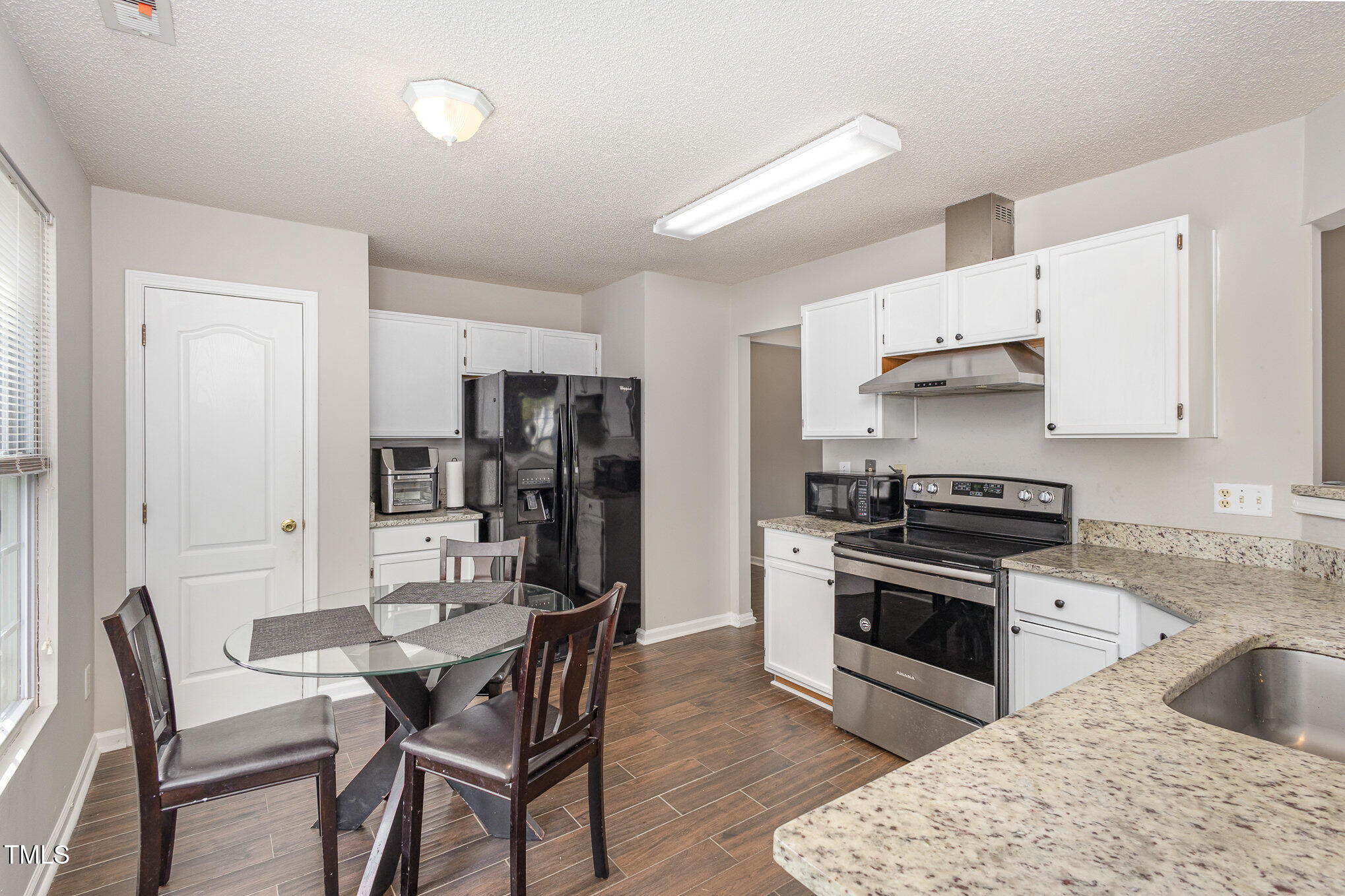 4331 Crowfield Drive Raleigh, NC 27610 - Photo 11 of 26 a kitchen with stainless steel appliances kitchen island granite countertop a sink a stove a refrigerator cabinets and a dining table