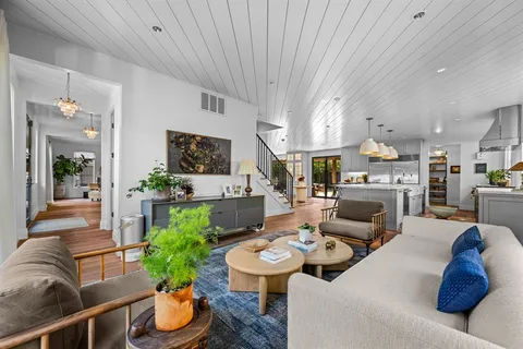 a living room with furniture kitchen view and a chandelier