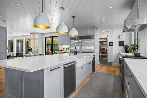a large kitchen with stainless steel appliances a lot of counter space and a view of living room