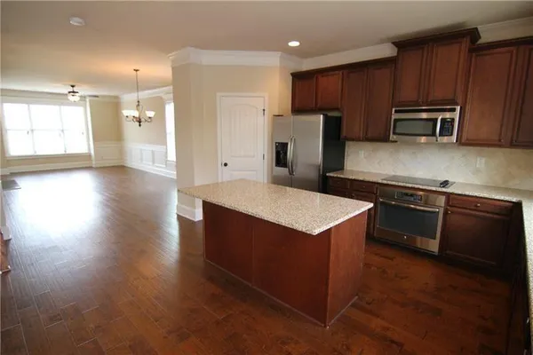 a kitchen with stainless steel appliances granite countertop a refrigerator a sink a stove a microwave and wooden floor