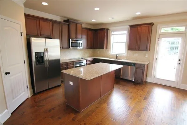 a kitchen with kitchen island granite countertop a sink a stove a refrigerator cabinets and a counter top space