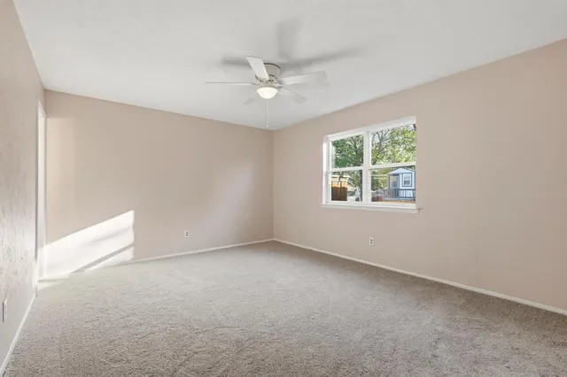 an empty room with a window and a fan