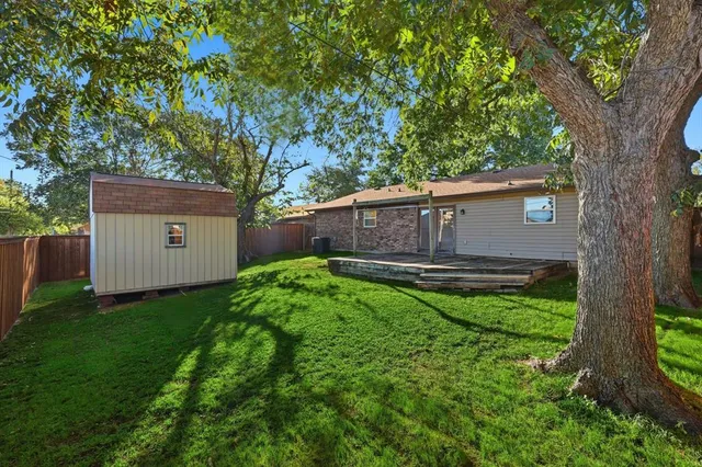 a view of a house with a large tree and a yard with plants and large trees