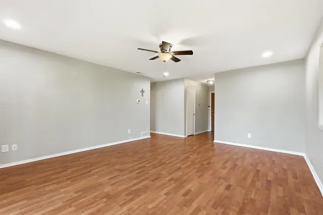a view of an empty room with a ceiling fan and wooden floor