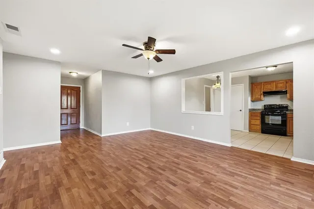 a view of an empty room with window and a kitchen