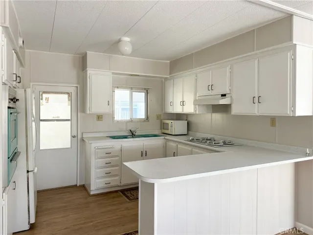 a kitchen with cabinets appliances and wooden floor