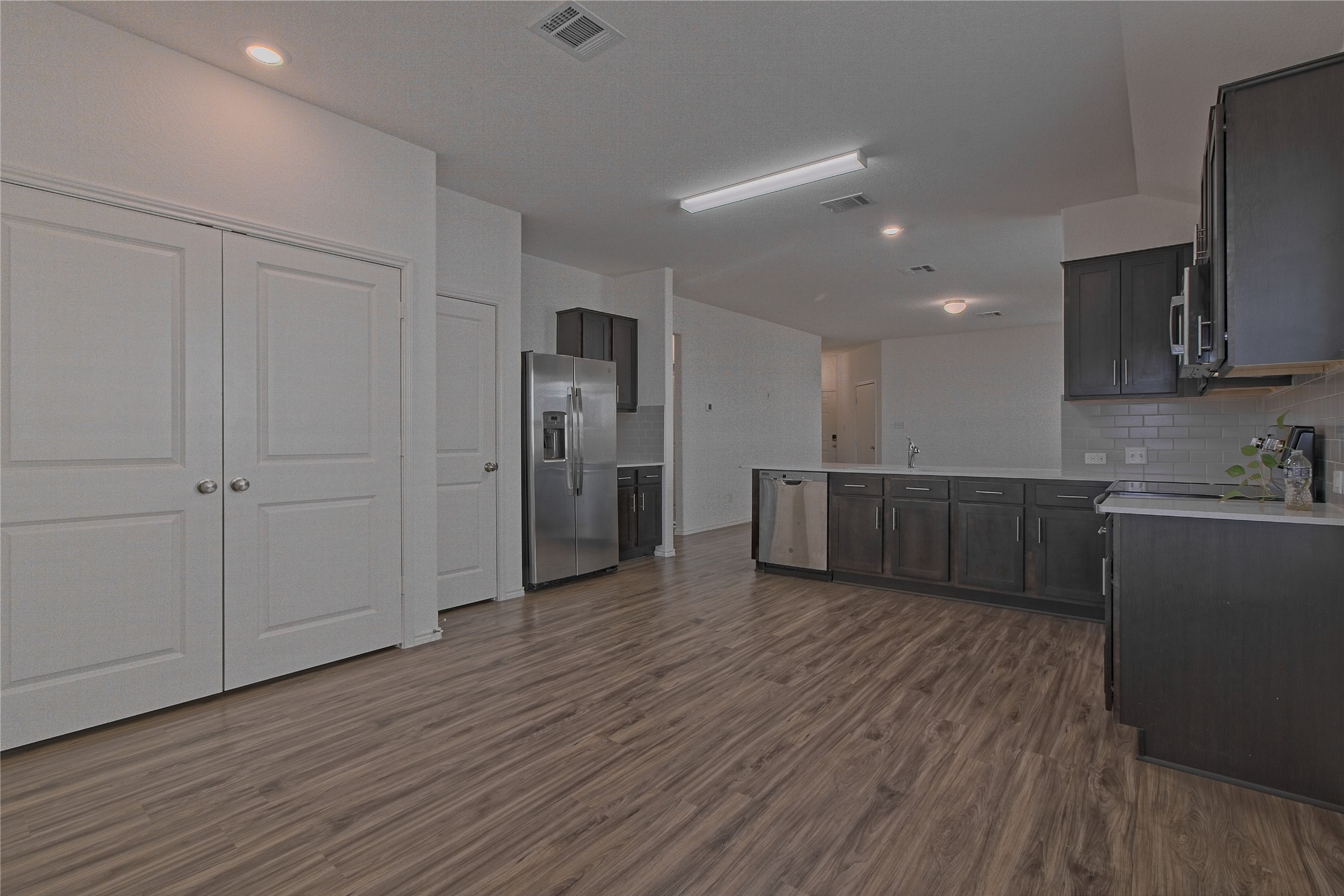 505 Greatest Gift Way Jarrell, TX 76537 - Photo 12 of 30 Kitchen with a peninsula, appliances with stainless steel finishes, dark wood-type flooring, light stone countertops, and decorative backsplash