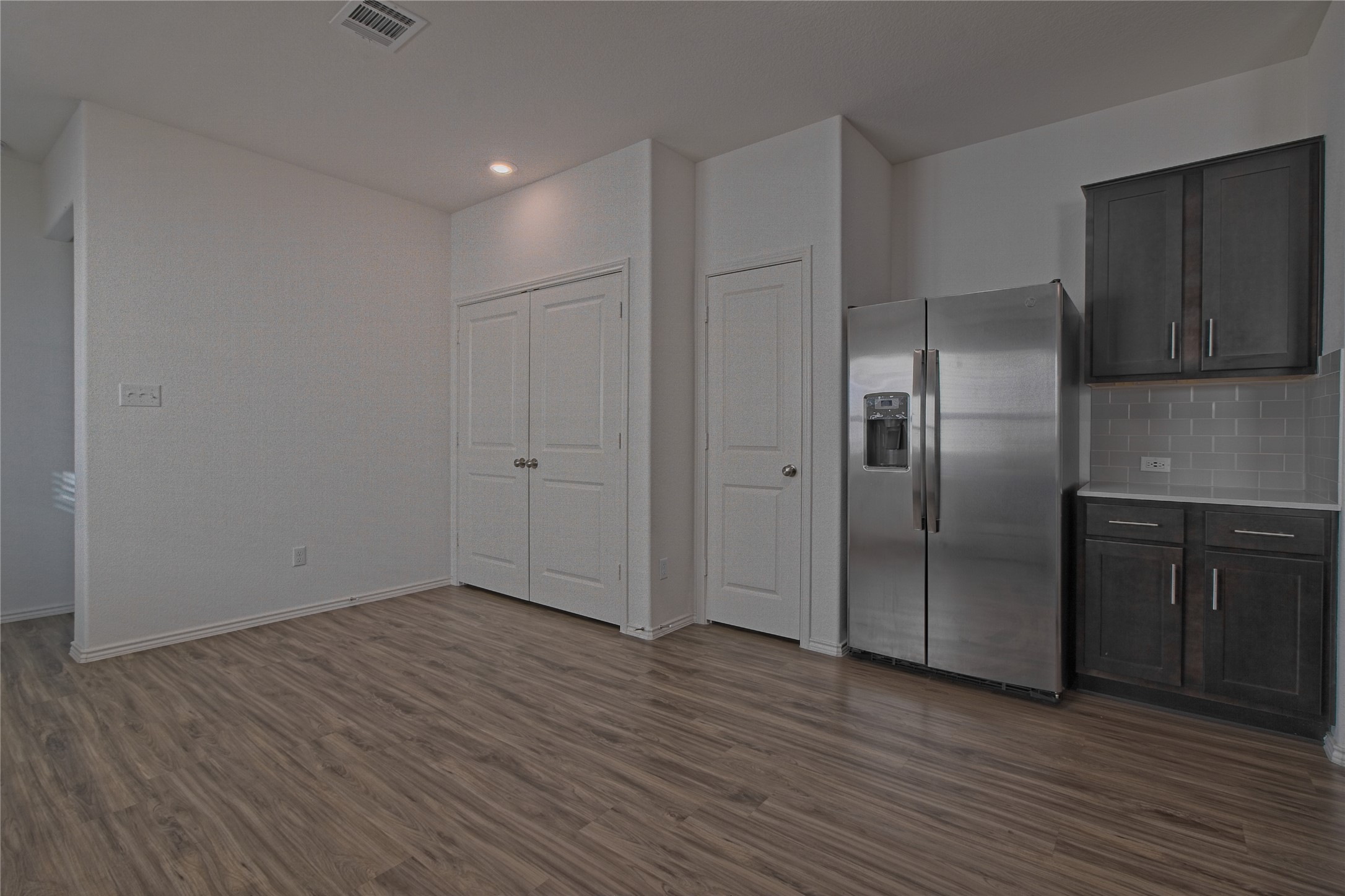 505 Greatest Gift Way Jarrell, TX 76537 - Photo 14 of 30 Kitchen featuring stainless steel fridge with ice dispenser, dark wood-style flooring, recessed lighting, dark brown cabinetry, and backsplash