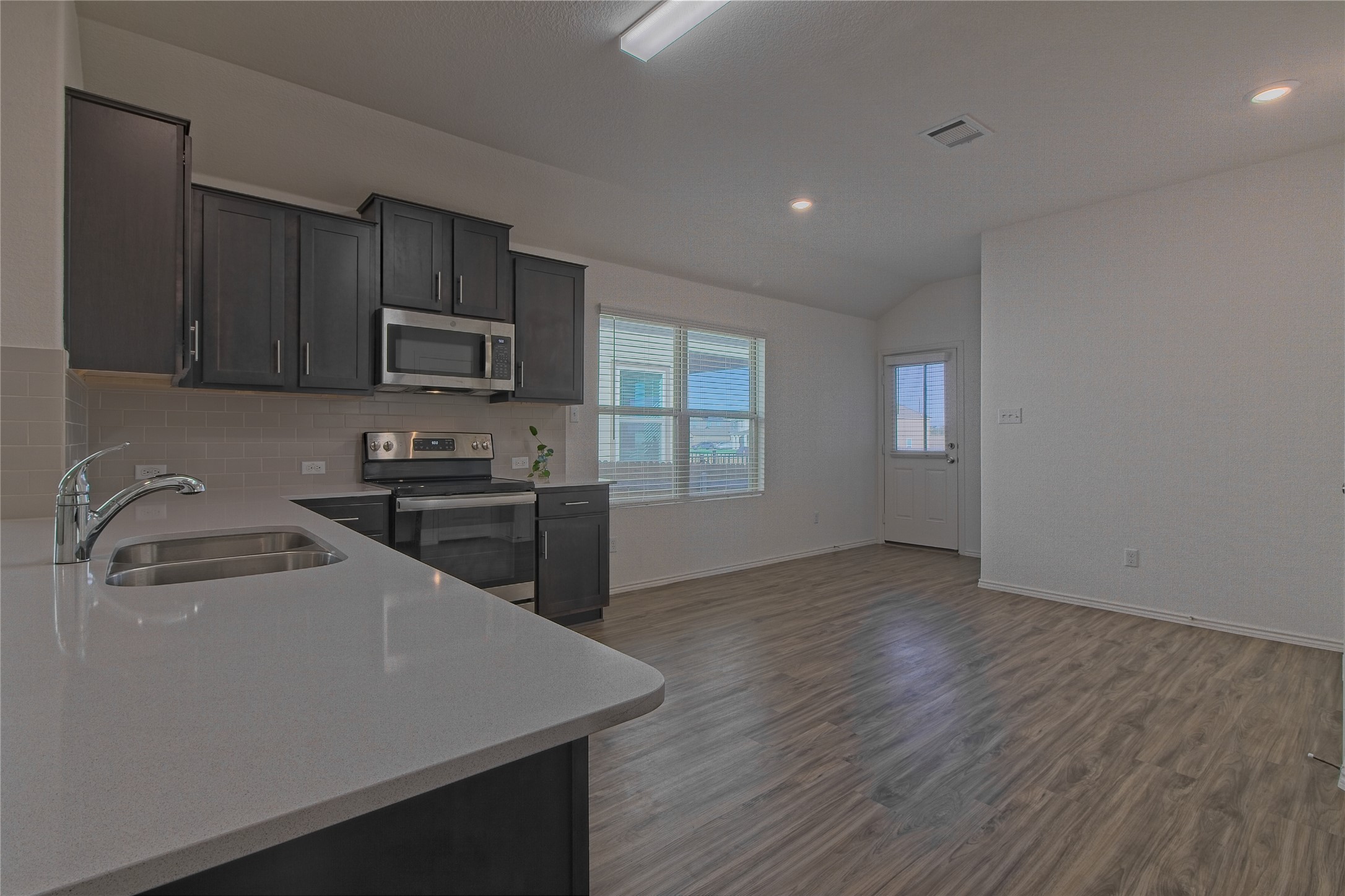 505 Greatest Gift Way Jarrell, TX 76537 - Photo 9 of 30 Kitchen featuring stainless steel appliances, dark wood-type flooring, lofted ceiling, light stone countertops, and backsplash