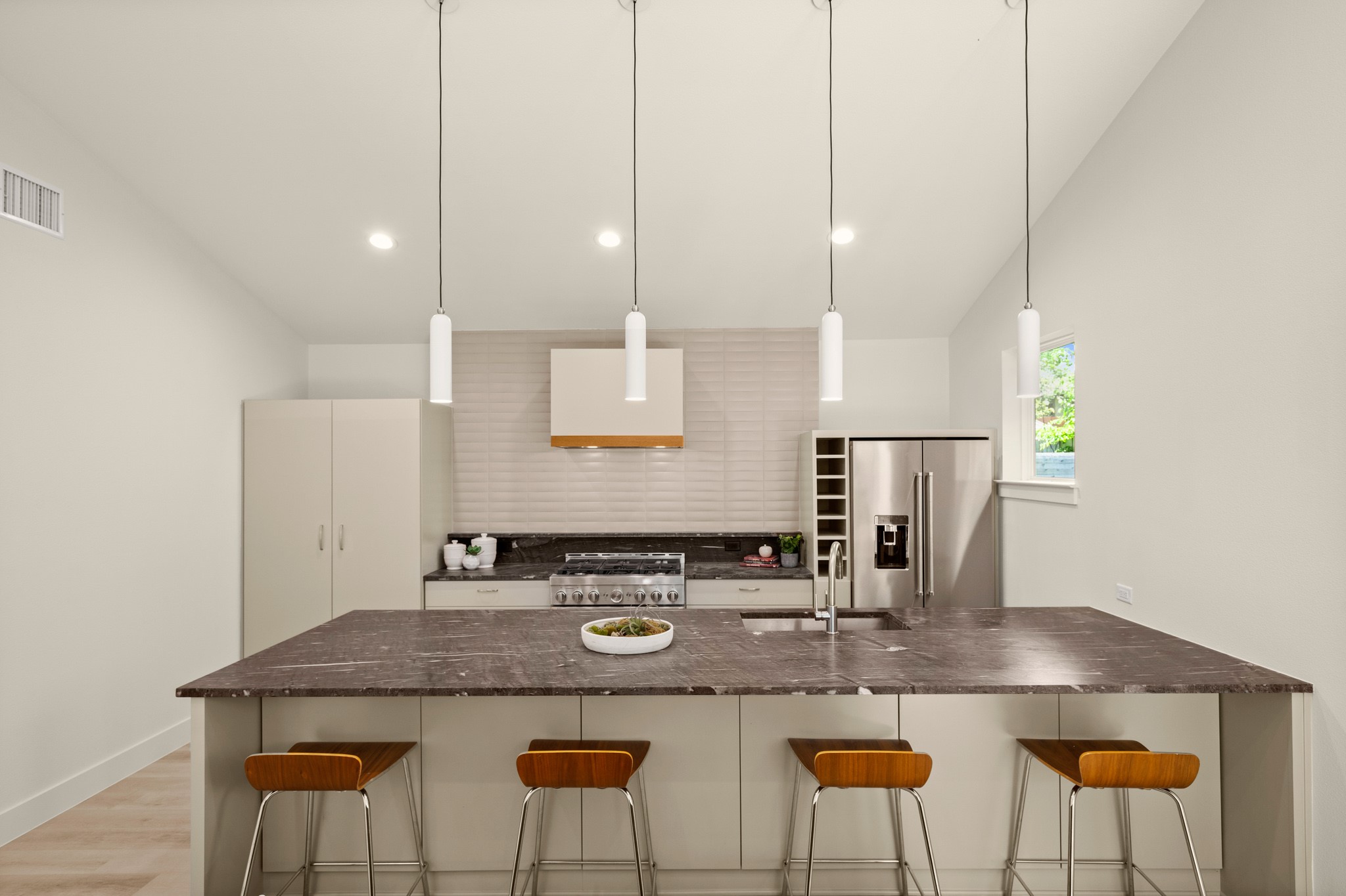 3003 Ray Wood Drive, Unit 2 Austin, TX 78704 - Photo 13 of 28 Kitchen with lofted ceiling, a kitchen breakfast bar, stainless steel appliances, pendant lighting, and dark stone counters