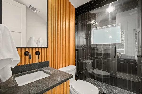 a bathroom with a granite countertop sink a toilet and shower
