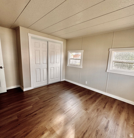158 Cushing Way Layton, UT 84041 - Photo 11 of 14 Interior room featuring wood-finish flooring, two large sliding closet doors with paneled detailing, and two windows providing natural illumination