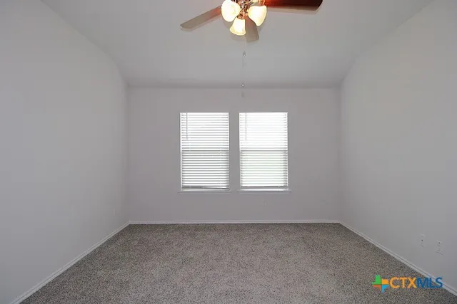 an empty room with a chandelier fan and windows