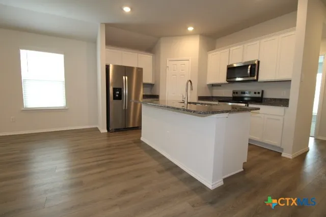 a kitchen with stainless steel appliances granite countertop a refrigerator a stove top oven a sink and dishwasher with wooden floor