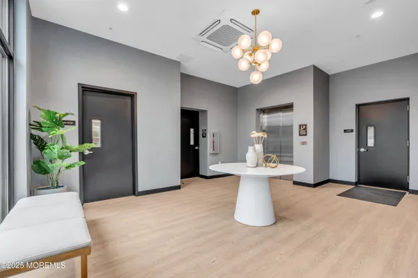 a view of a white painted room with chandelier and wooden floor
