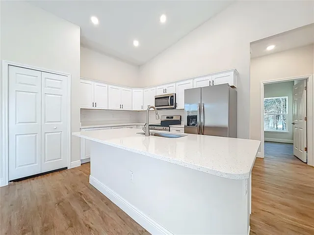 a large white kitchen with wooden floor and a sink