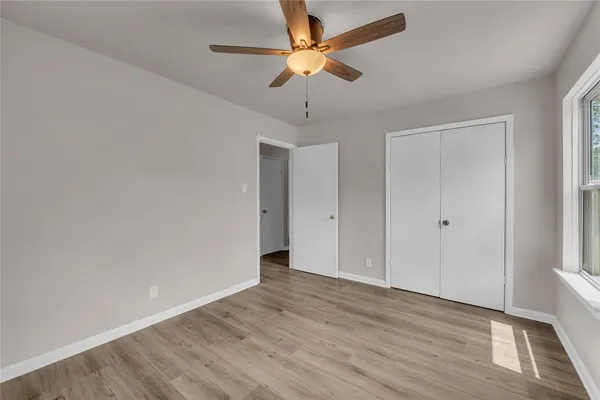 a view of an empty room with window and wooden floor