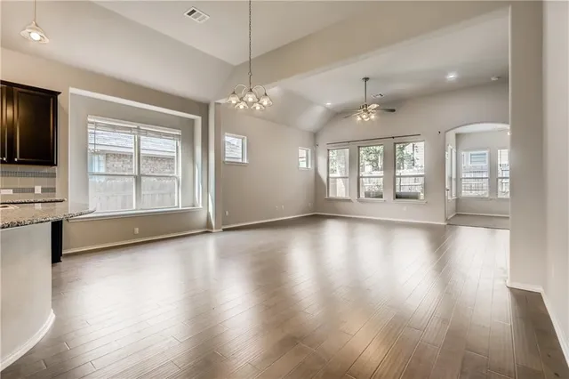 an empty room with wooden floor fireplace and windows