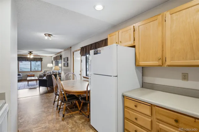 a kitchen with a refrigerator a dining table and chairs