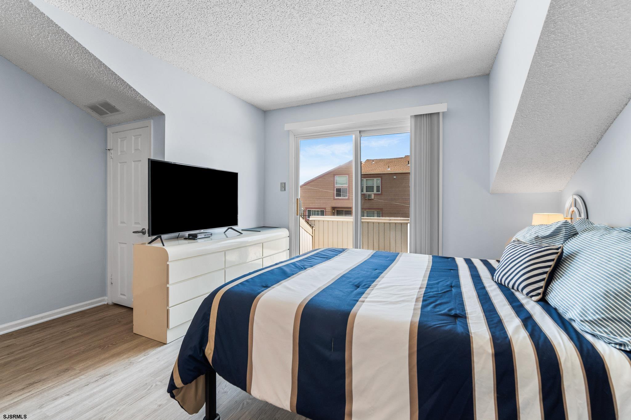 323 44th Street South, Unit 23 Brigantine, NJ 08203 - Photo 19 of 33 a bedroom with a bed and a flat tv screen on wall