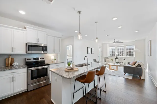 a kitchen with stainless steel appliances granite countertop a stove top oven a sink dishwasher a dining table and chairs with wooden floor