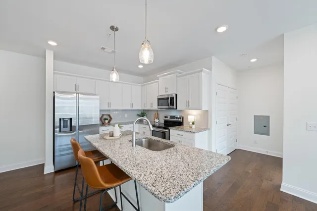 a kitchen with kitchen island granite countertop a sink and refrigerator