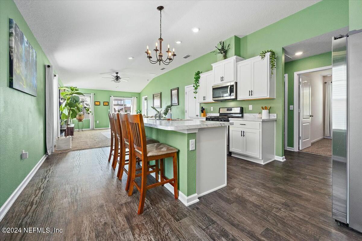 231 Caminha Circle St. Augustine, FL 32084 - Photo 3 of 15 a open kitchen with stainless steel appliances granite countertop a refrigerator a stove top oven a dining table and chairs with wooden floor