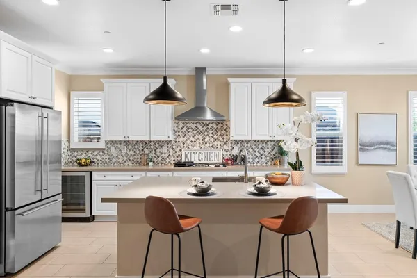 a kitchen with stainless steel appliances a sink dishwasher stove refrigerator and couches with wooden floor