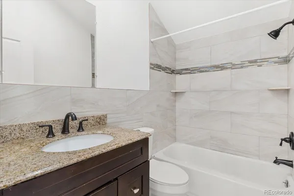 a bathroom with a granite countertop sink toilet and bathtub