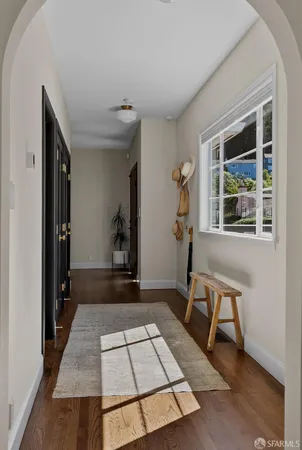 a view of a hallway with wooden floor and a living room