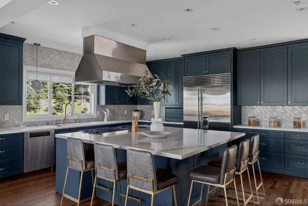 a kitchen with stainless steel appliances a dining table chairs and wooden floor