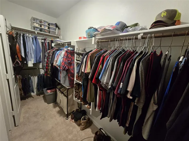 a view of walk in closet with clothes and shoes