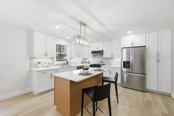 a kitchen with a sink a refrigerator a stove and white cabinets