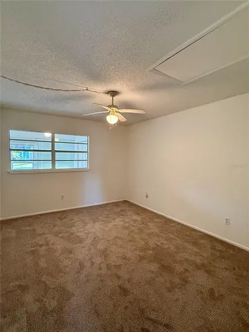 an empty room with a chandelier fan and windows