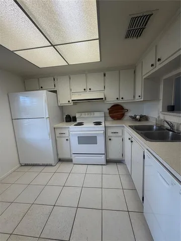 a kitchen with cabinets a sink and white appliances