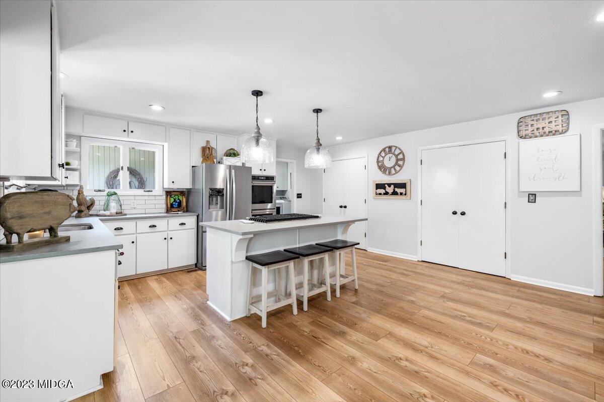 724 Forest Hill Road Macon, GA 31210 - Photo 15 of 46 a kitchen with stainless steel appliances kitchen island wooden floors and white cabinets