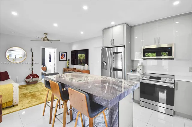 a kitchen with stainless steel appliances kitchen island granite countertop a stove a refrigerator a oven a sink with island and chairs