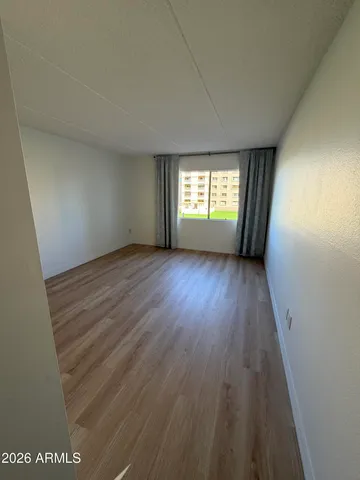 an empty room with wooden floor and windows