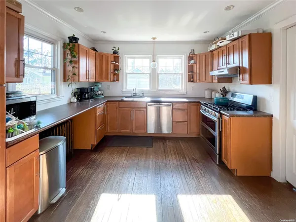 a kitchen with stainless steel appliances granite countertop wooden floors a stove a sink and a window