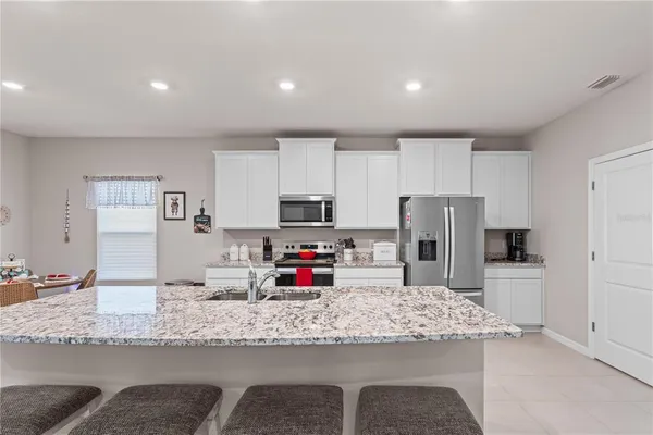 a kitchen with granite countertop a refrigerator and a stove top oven