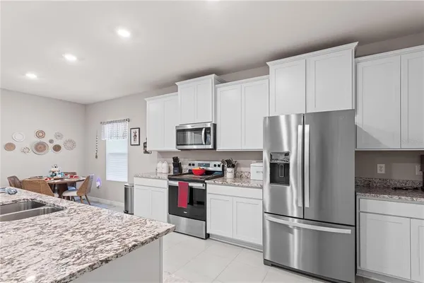 a kitchen with stainless steel appliances granite countertop a refrigerator stove a sink dishwasher and white cabinets with wooden floor