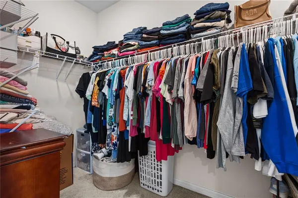 a view of walk in closet with clothes and shoes