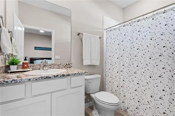 a bathroom with a granite countertop sink a toilet and a mirror