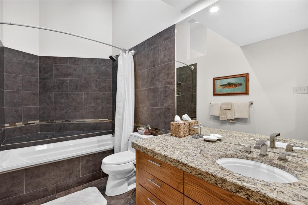 1080 North Greenbrier Road Nocona, TX 76255 - Photo 26 of 40 Bathroom featuring a tiled tub/shower combination, integrated storage bench, and a modern vanity with a single basin sink