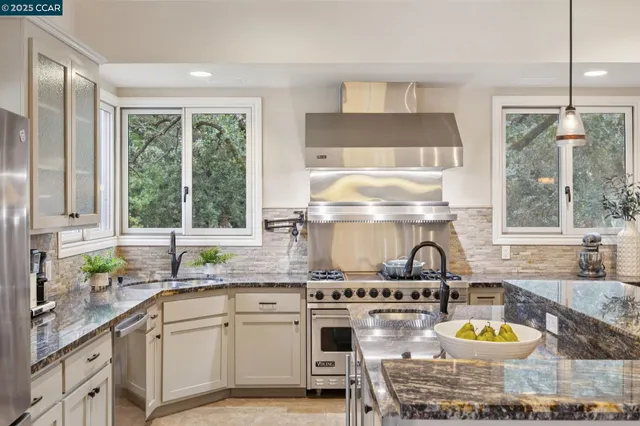 a kitchen with stainless steel appliances granite countertop a sink stove and cabinets